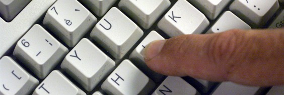 Nærbillede af et udsnit af et edb tastatur og en finger